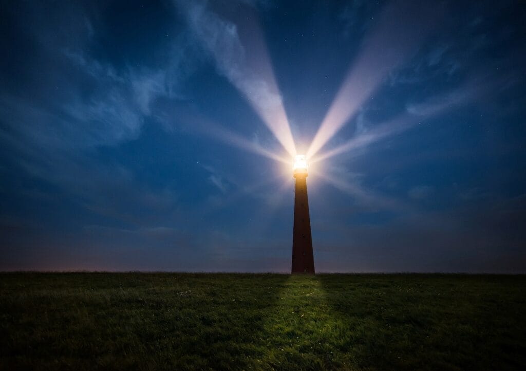 Image of a lit up lighthouse at night along a shore, viewed from the land side. SmartBrief story about how brands can contribute to national healing